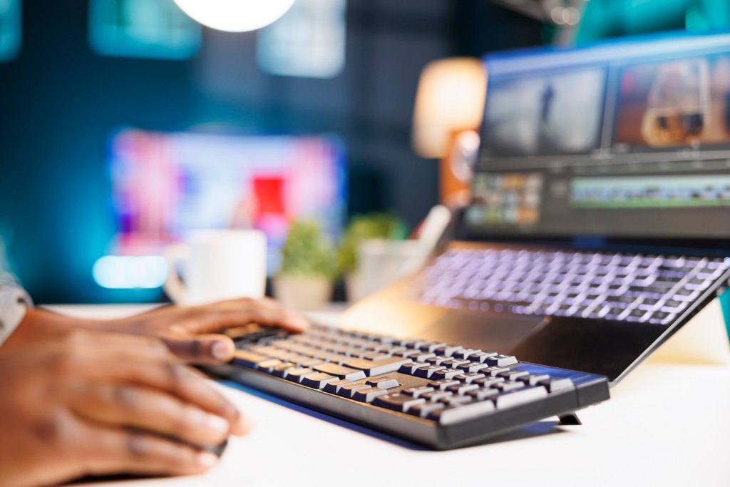 Black individual edits footage on laptop