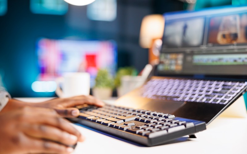 Black individual edits footage on laptop