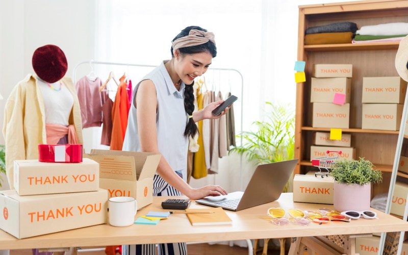 Starting small businesses SME owners female entrepreneurs Use a laptop to receive and review orders online to prepare to pack boxes, sell to customers, SME online business.